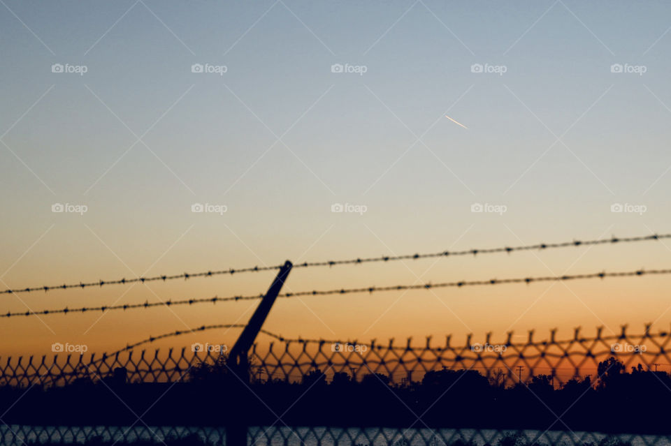 Behind barbed wire fence during sunset 