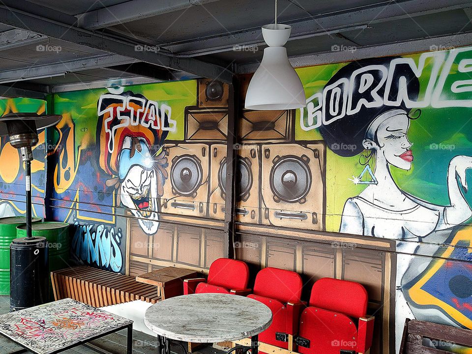 Urban art.  Graffiti on the wall.  Pirate and woman.  There are armchairs and a table along the wall.