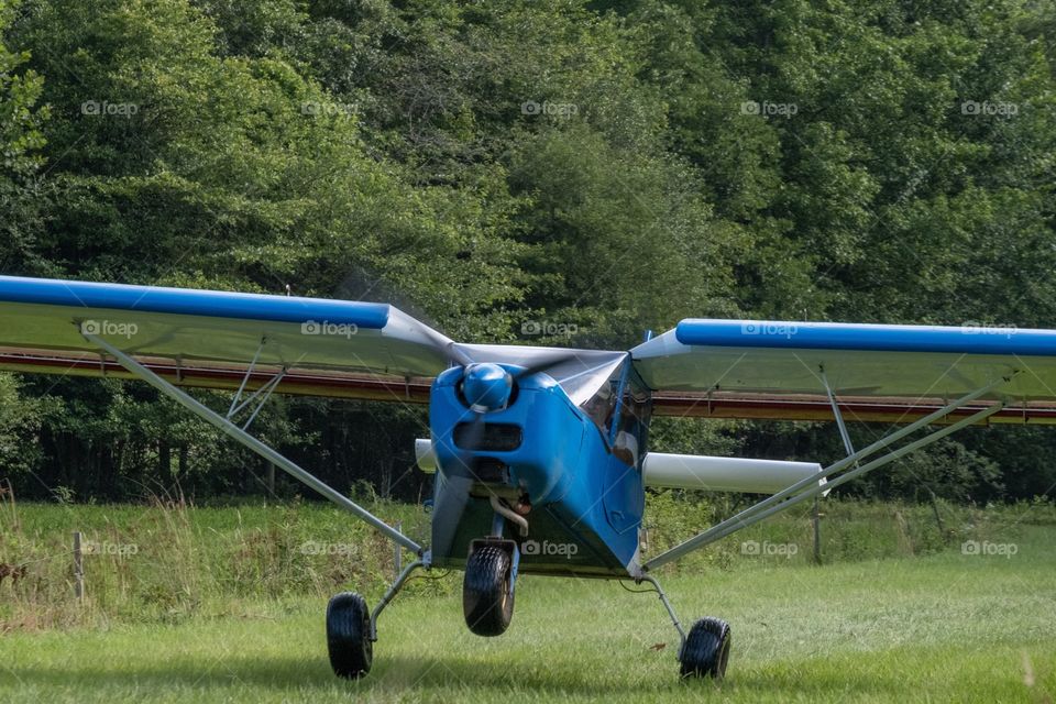 A pilot takes off in his two-seater airplane from his pasture runway to enjoy some aerial site-seeing. 