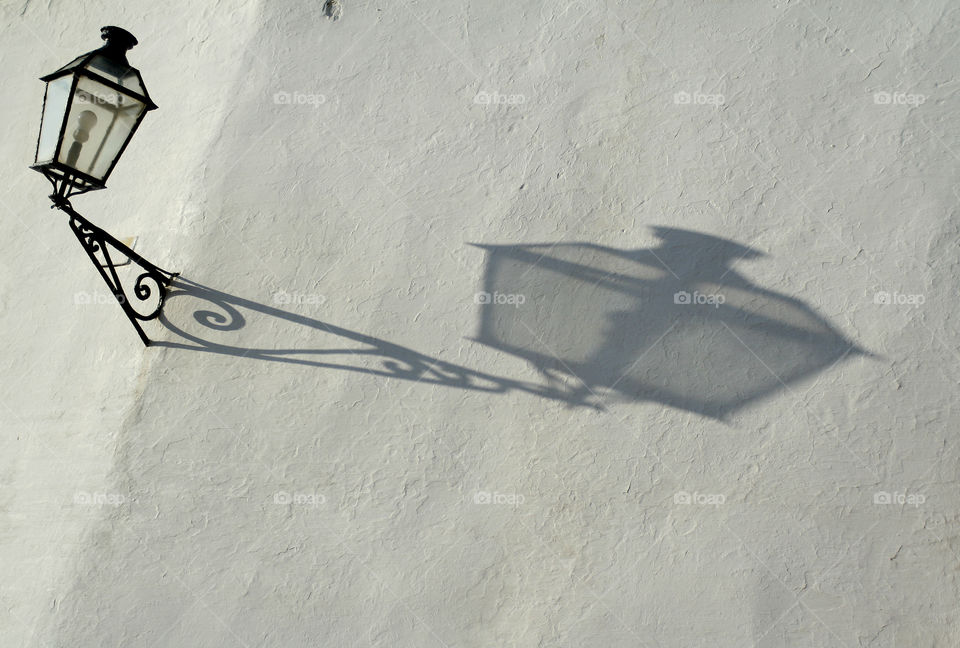 Reflection of a street lamp on a white wall in Spain