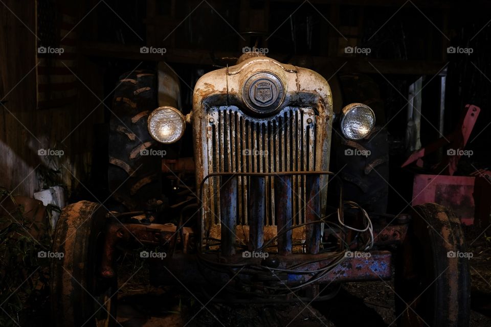 Front view of a 1953 Ford Jubilee vintage tractor under the dim light of a lantern in a barn. It is still operational. 