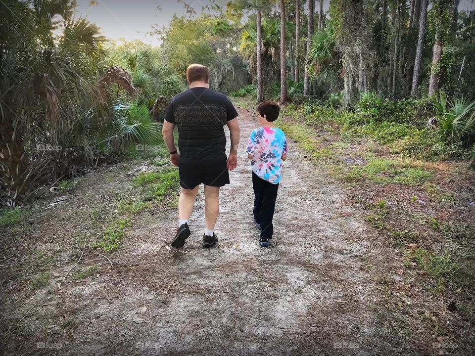 Father and son walking together through the forest.