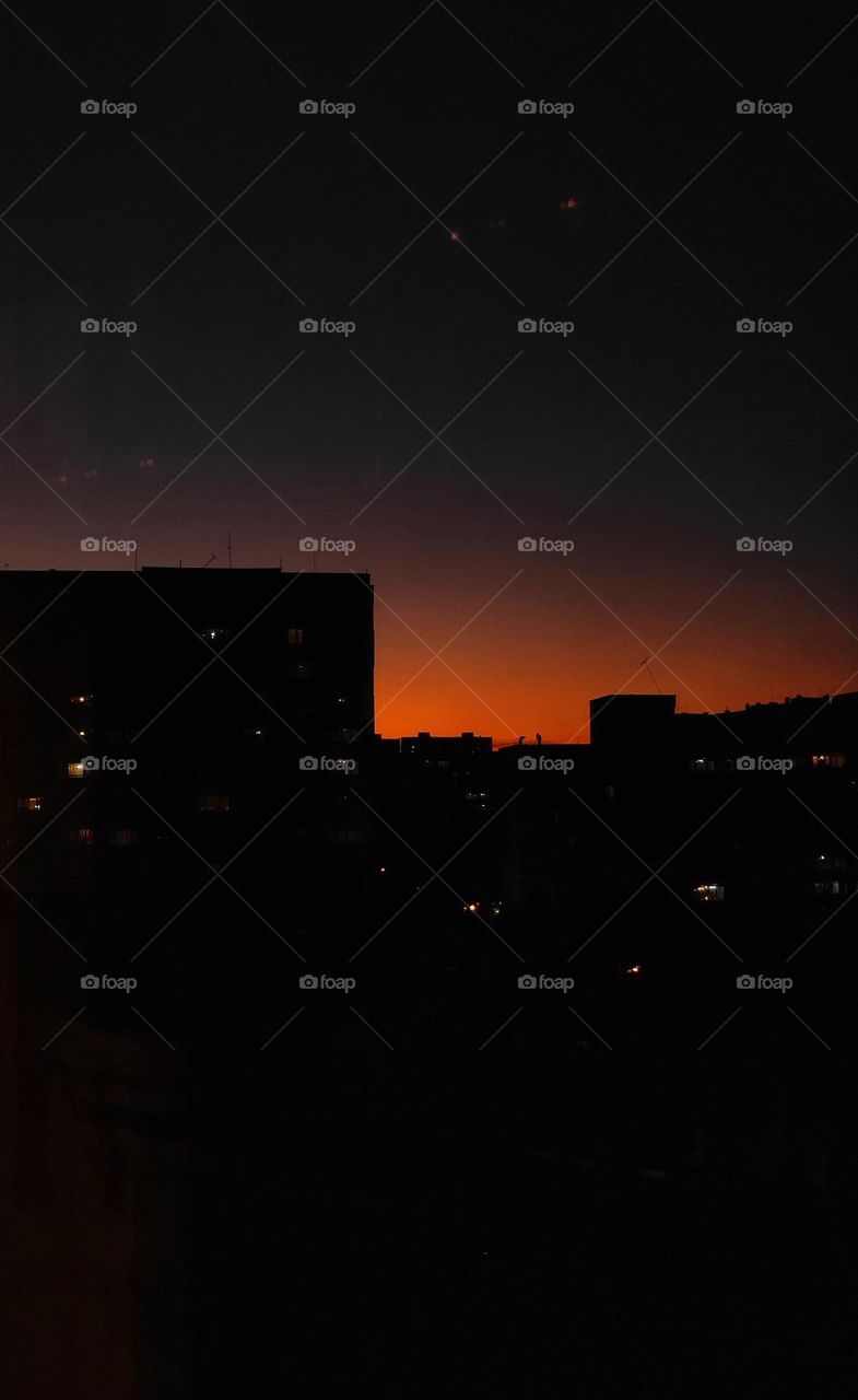 Setting sun over block of flats / Sunset behind apartment buildings / People working on the rooftop of a building