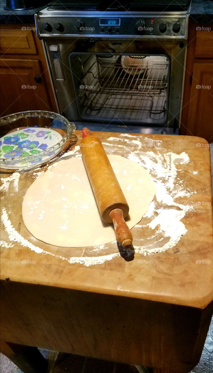 Homemade pie crust, rolling pin & pie plate ready to lay into pyrex glass pie plate.