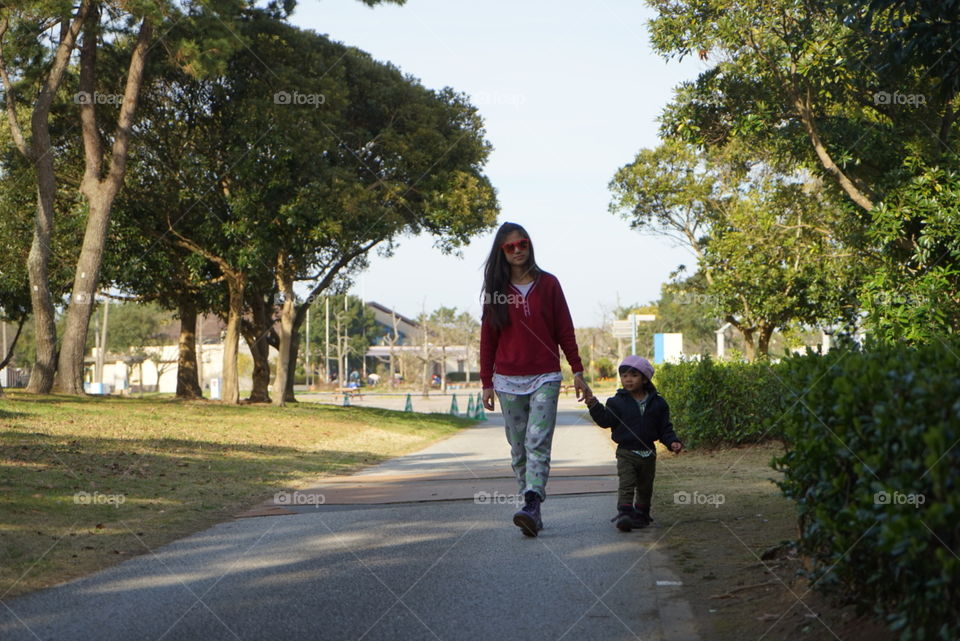 Mother holding child hand walking in park