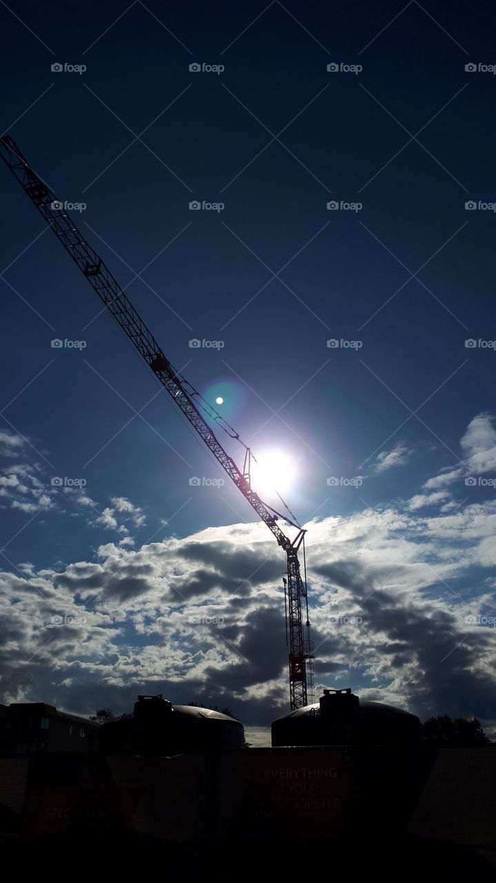 Sun Peeking Behind Red Crane with Sunspot