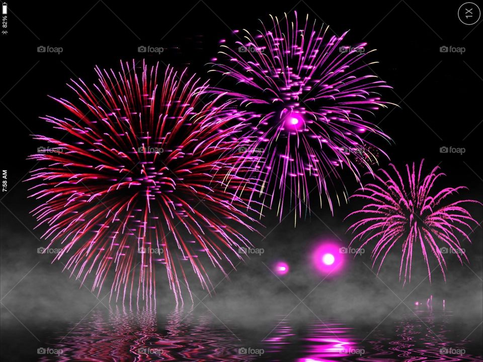 Sparkling pink fireworks reflected in water.