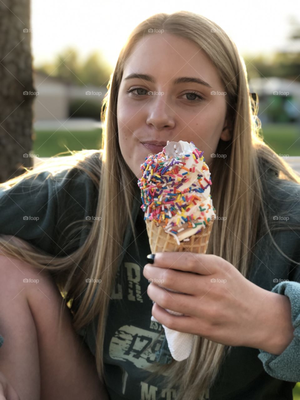 A twist Ice cream cone with sprinkles in hand of girl during a summer evening.