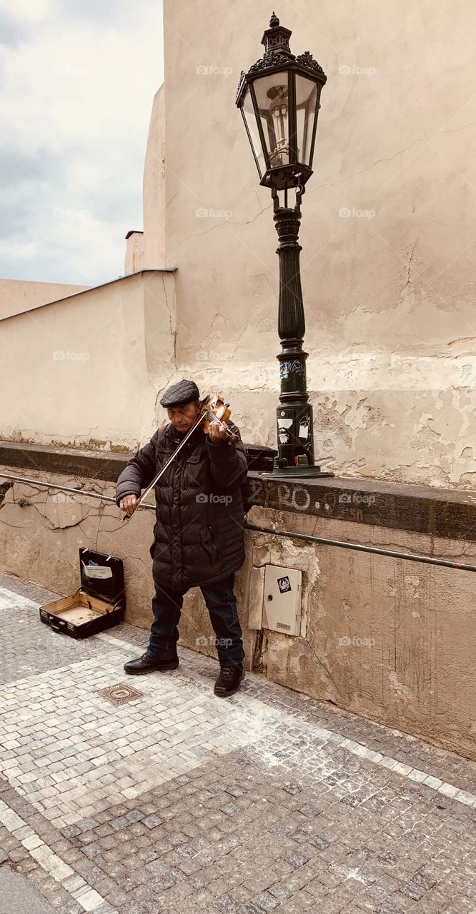 A old man playing a violin in the center of Prague. 