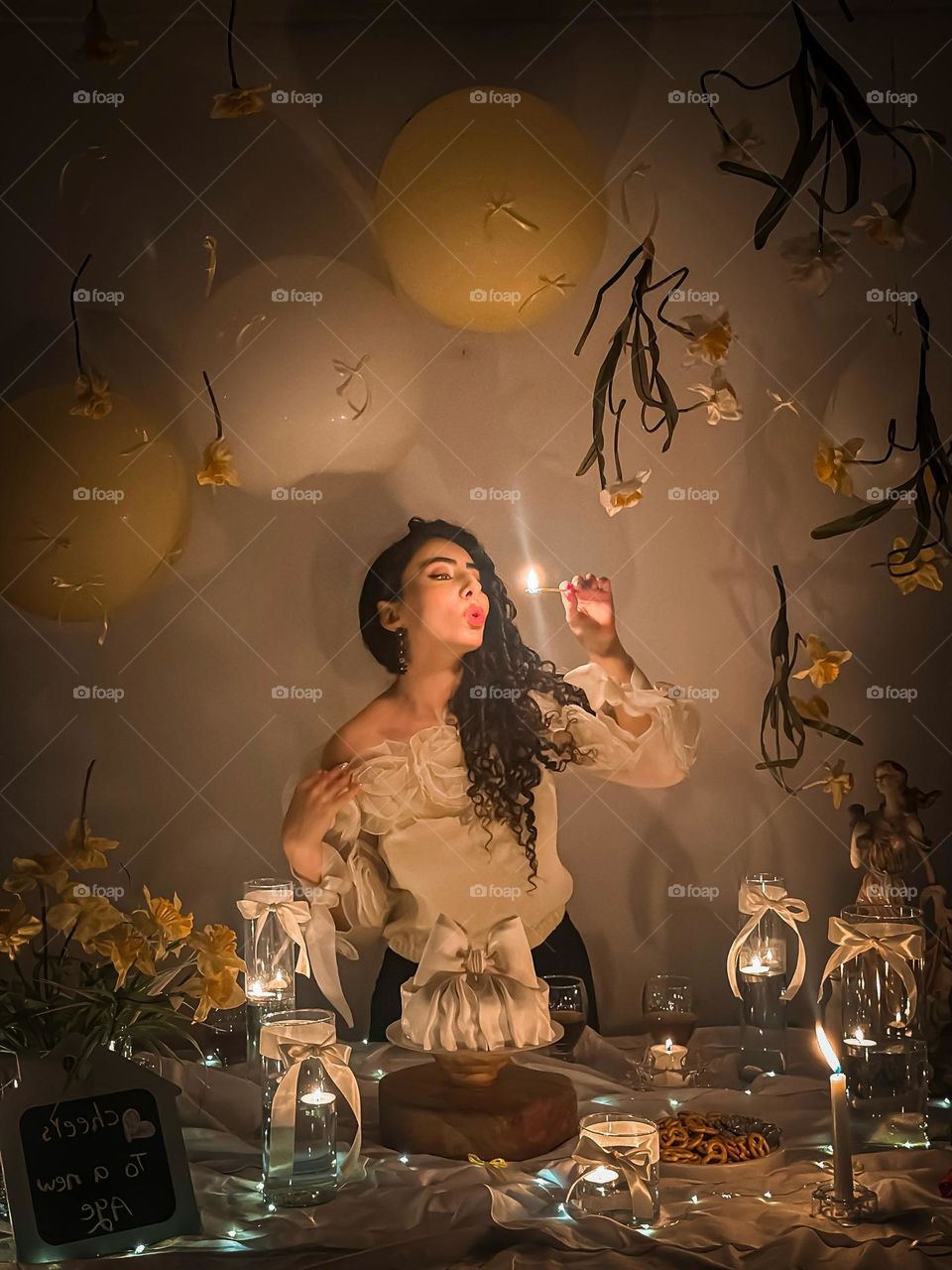 A cinamatic self-portrait that captures the dreamy essence of a personal ritual under soft candlelight. Floating flowers and golden balloons set a whimsical scene, as the subject lights a flame to welcome a symbolic new age. 