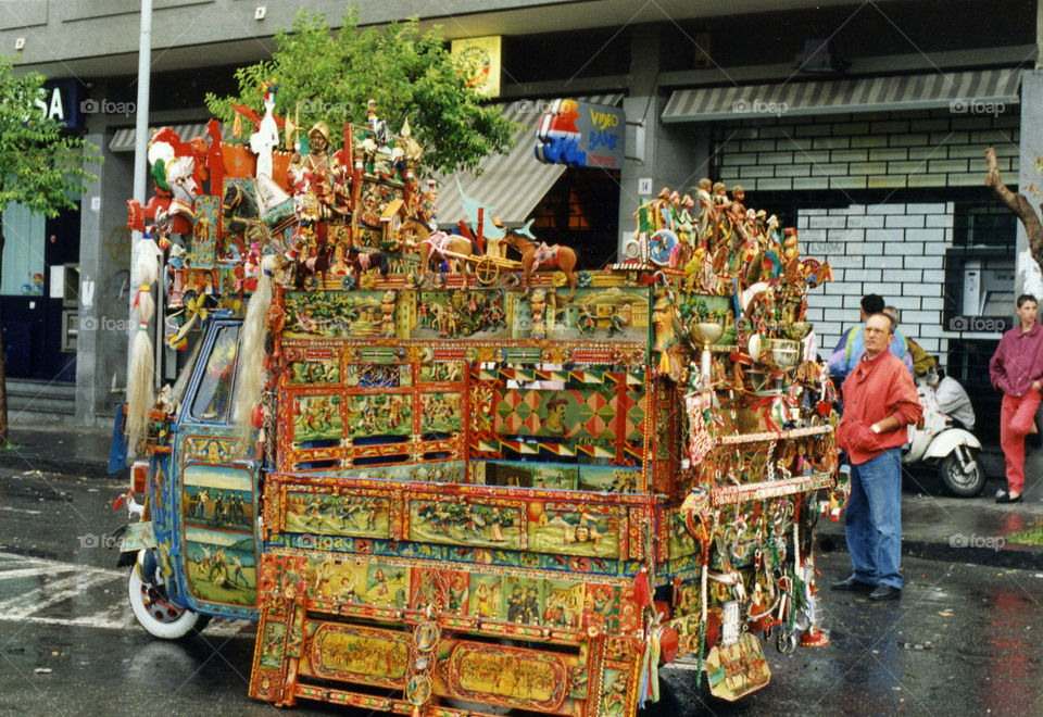 This is an APE car, a threewheeled motorcycle, sculpted and painted with images from the story of Orlando Furioso, the epic of Paladins of France. Sculpting and painting APE cars is a very recurring art form in Sicily. Artisan now almost disappeared.