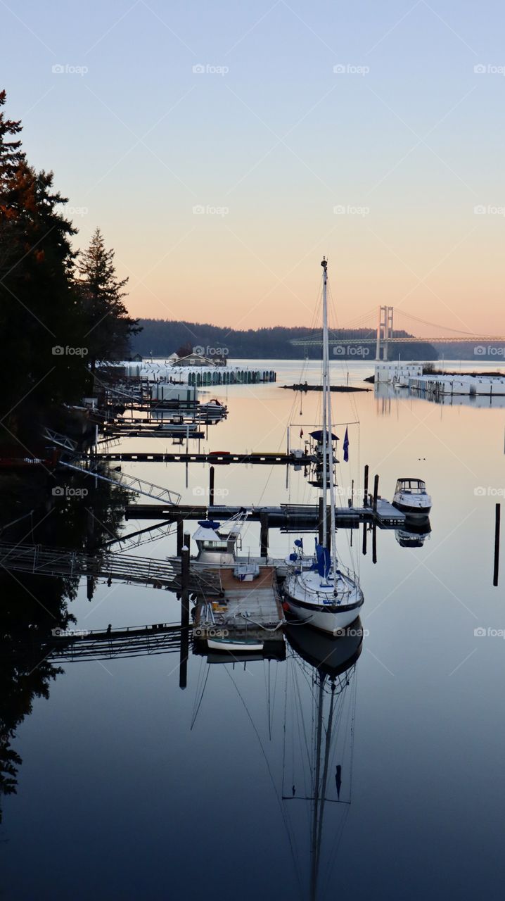 A sunset provides a glow over the docks of Day Island, Washington. The Narrows Bridge can be seen in the backdrop 