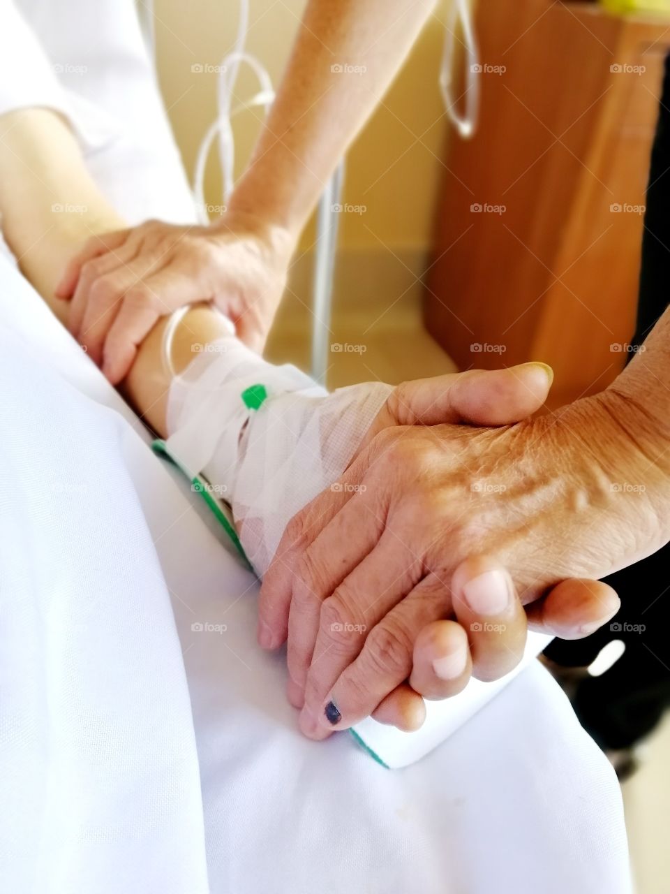 A wife holding the hand of her sick husband to show her love and support to him.