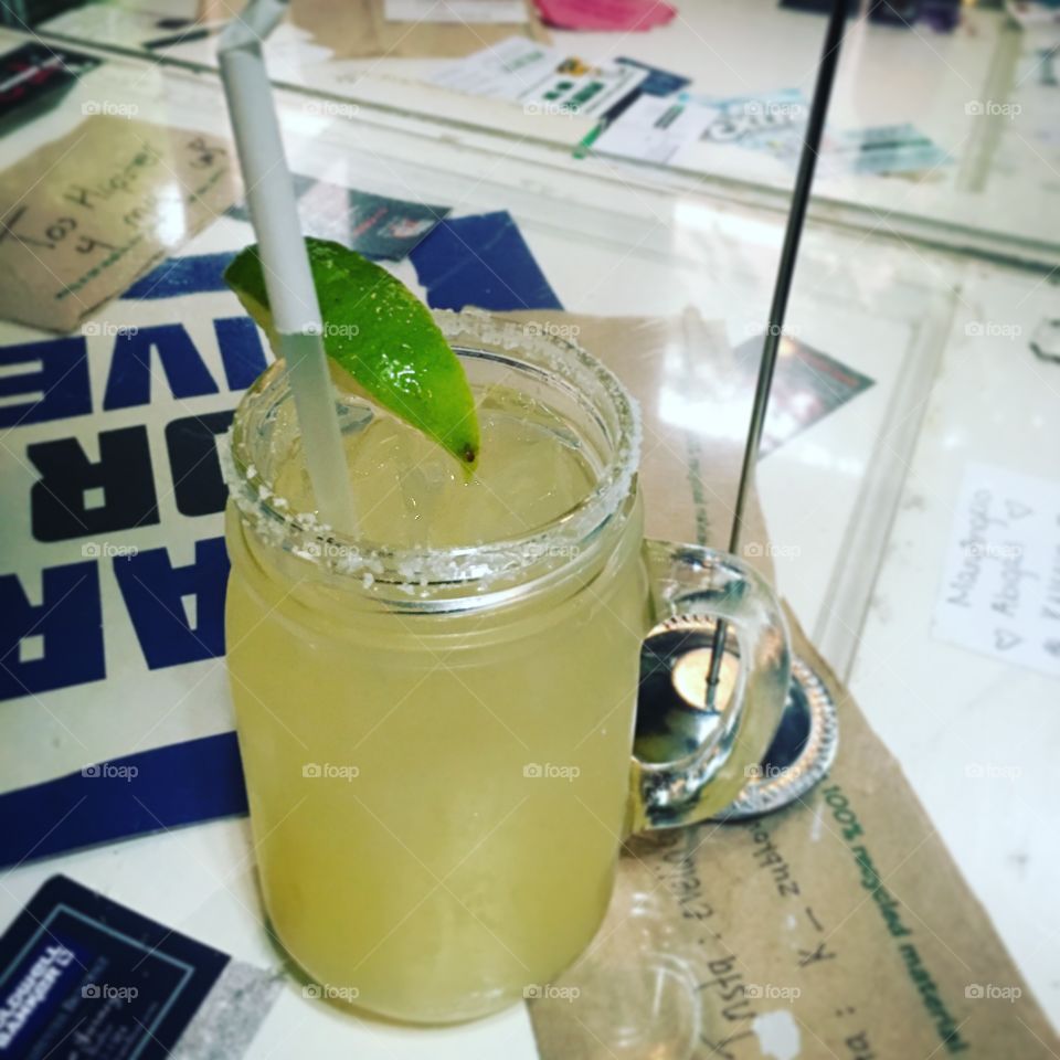 A lime margarita in a mason jar glass with salt on the rim.