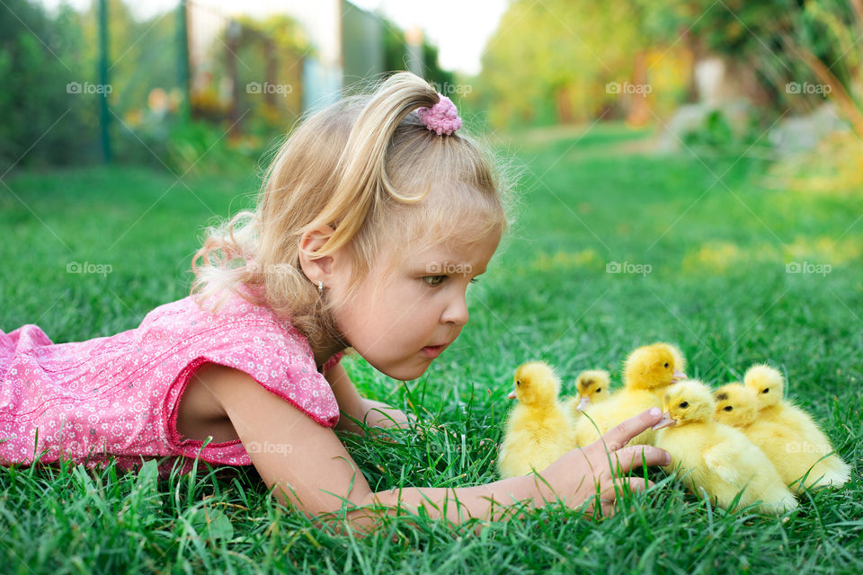 Little girl with chickens on grass