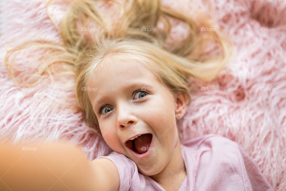 Little Caucasian girl with surprised face on pink