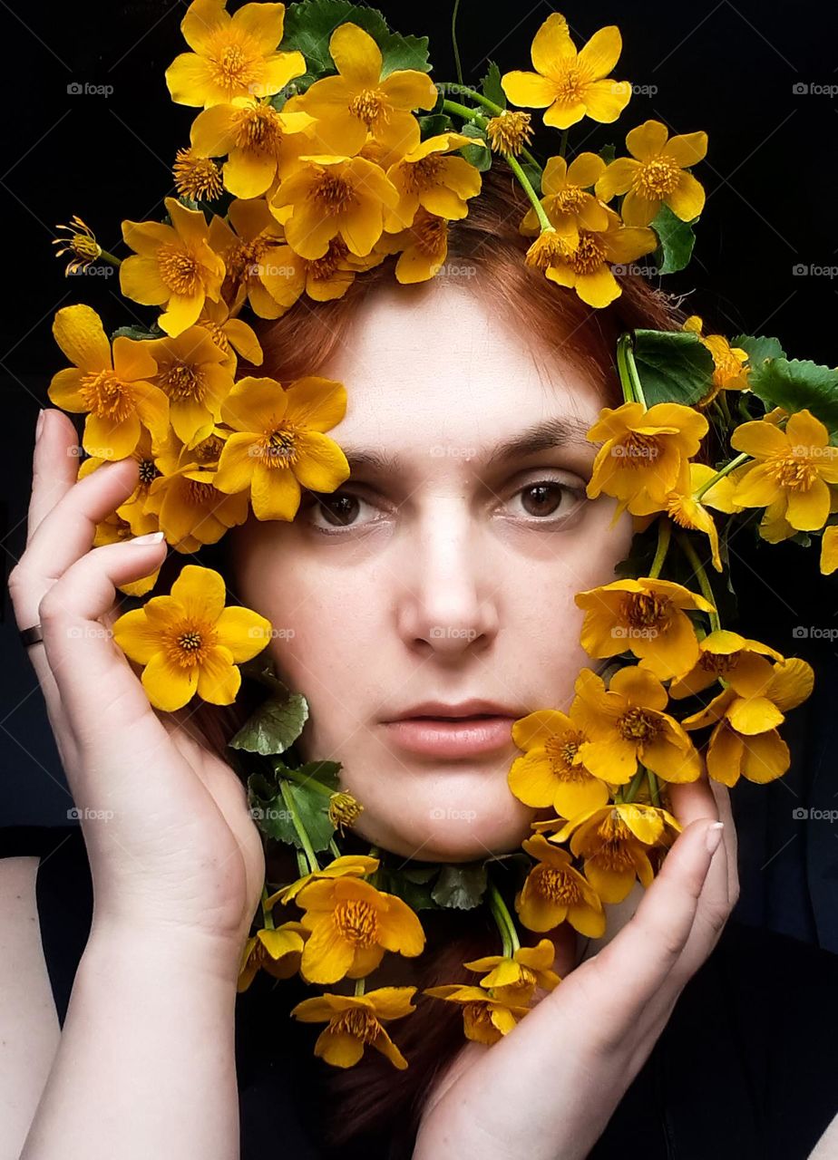 original spring portrait of a white-skinned girl with yellow flowers near her face, mobile photo