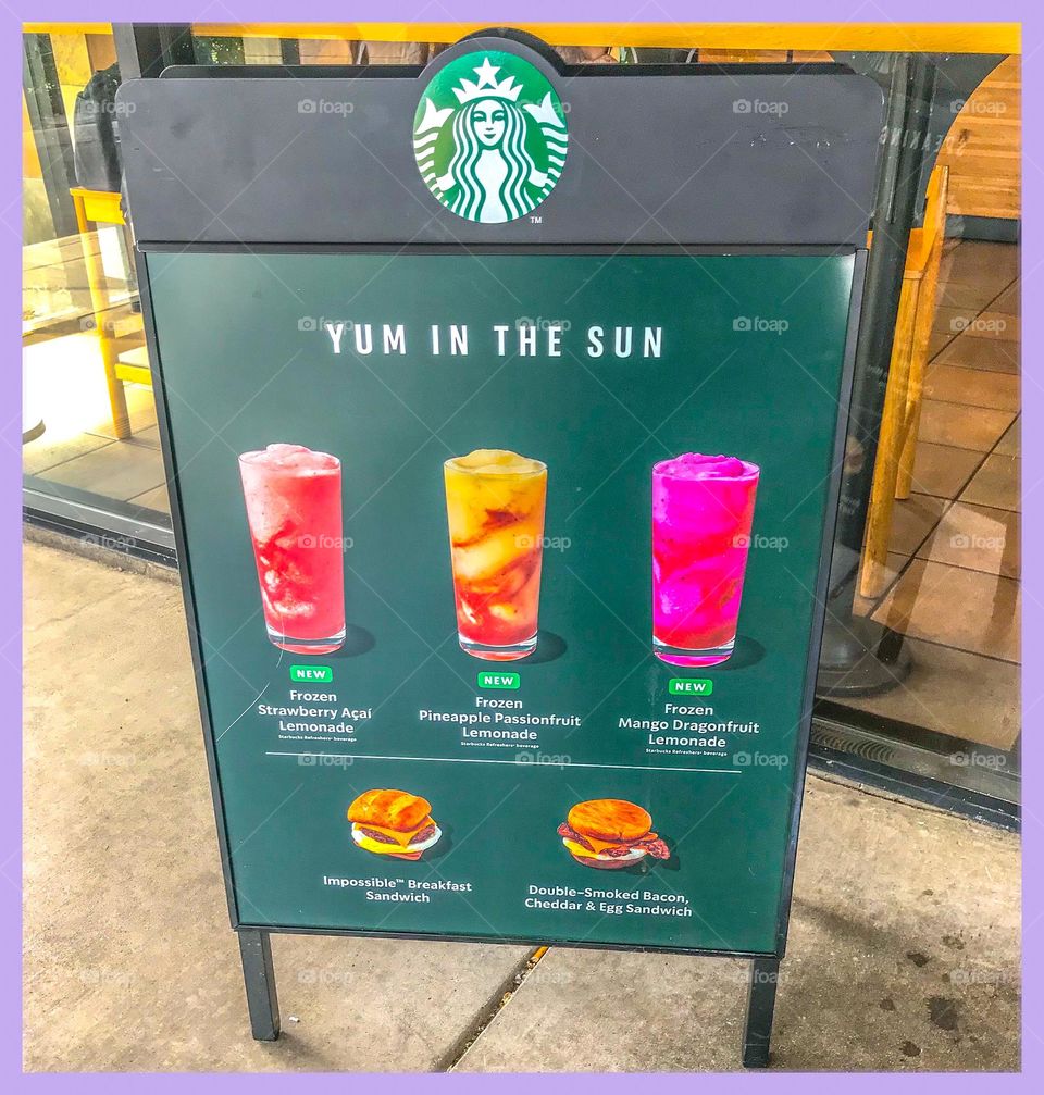A Starbucks display advertisement sign to attract paying customers interested in their drinks and edibles.