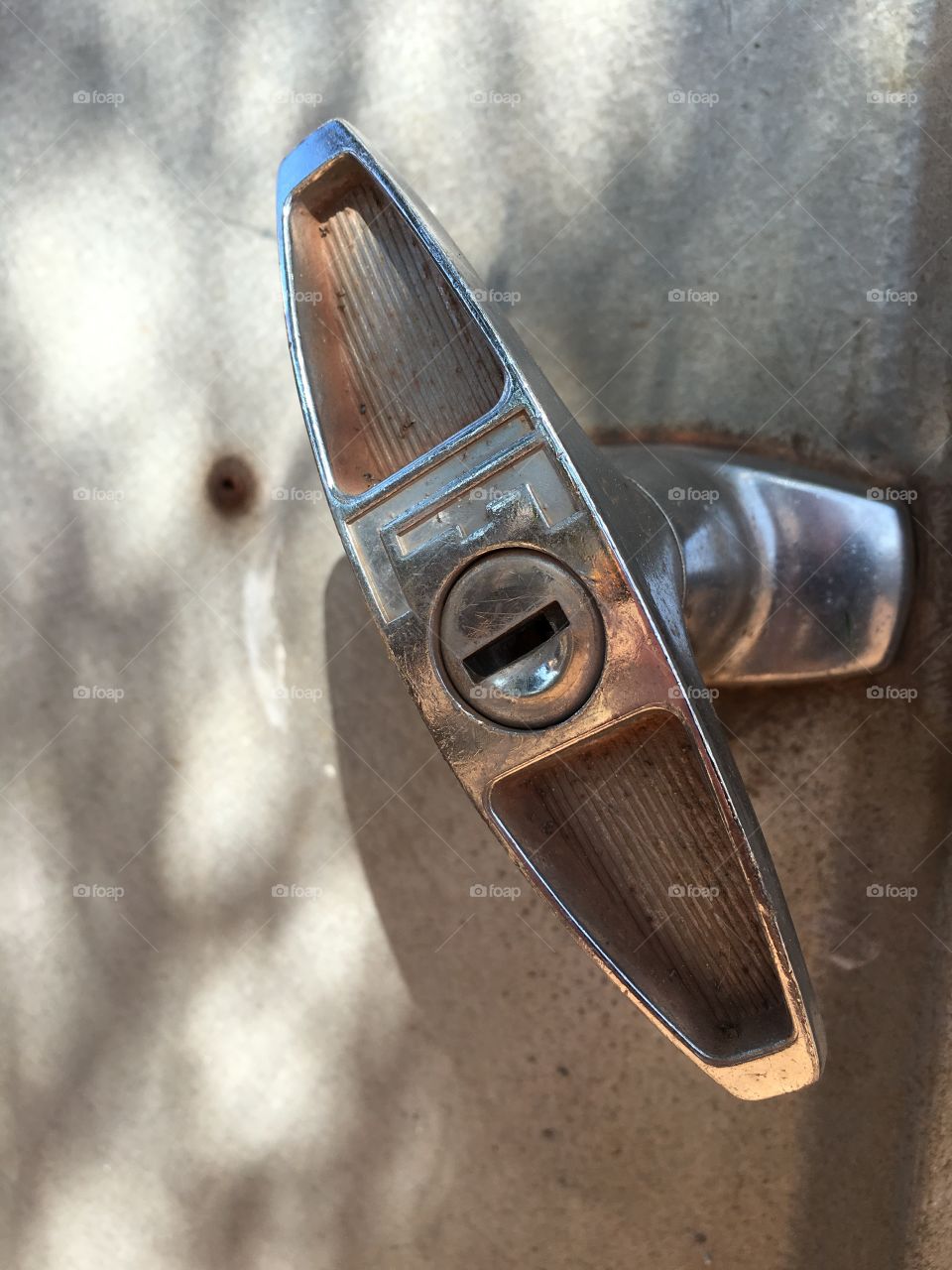 Grey stainless steel locking toggle handle on grey corrugated steel shed closeup