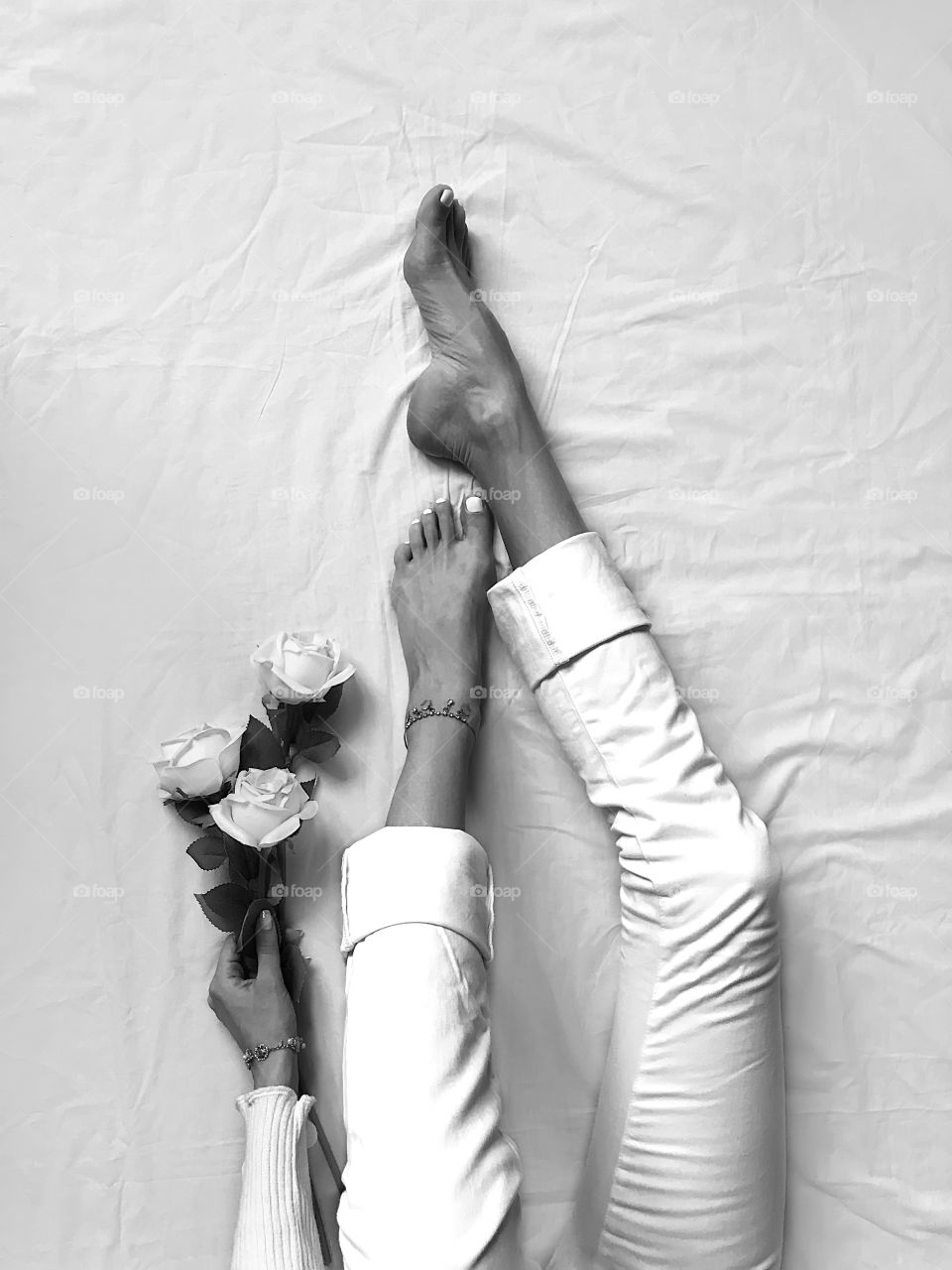 Young woman in white jeans with white roses in white bed