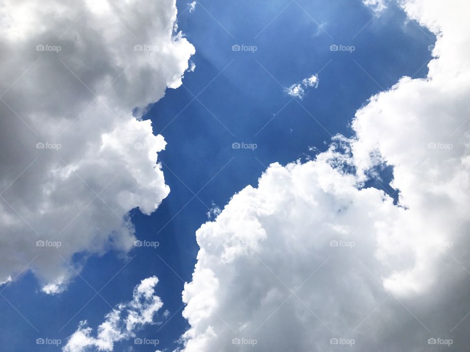 Bright blue sky with huge puffy white clouds! While others call these sunbeams, I call these Jesus Light! Perfect for stormy weather when you need some sunshine and some shade!