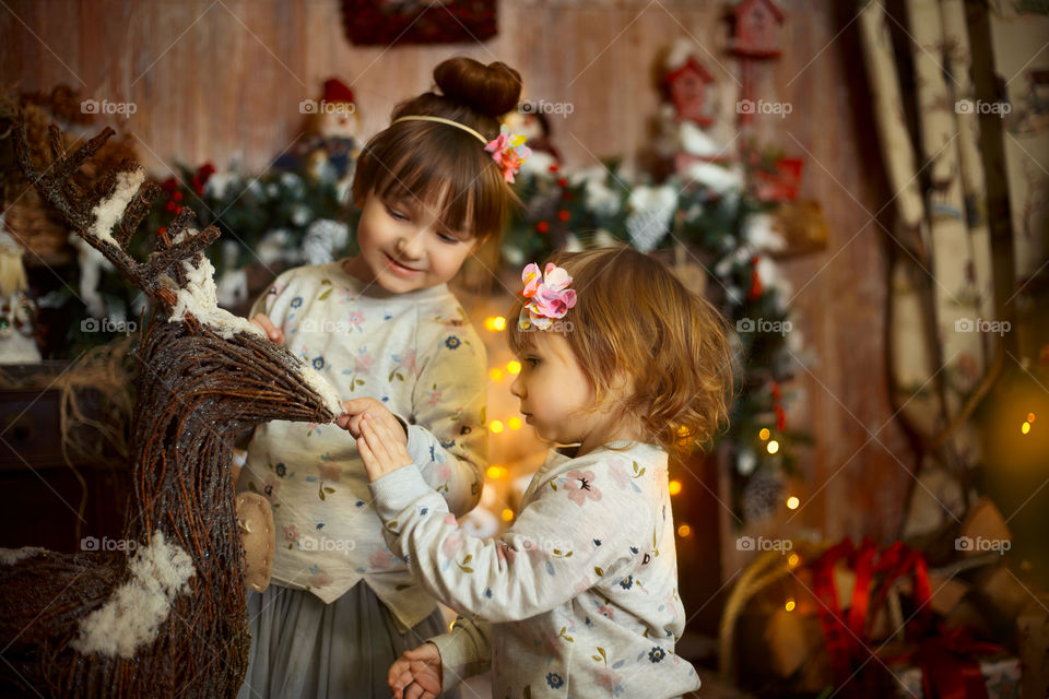 Little sisters near fireplace at Christmas Eve 