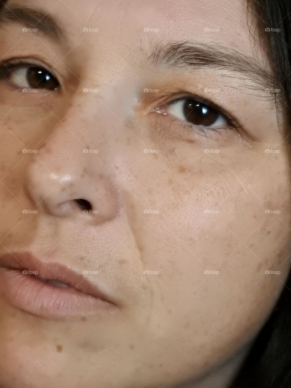 Face skin in the forties of a woman with freckles and brown hair.