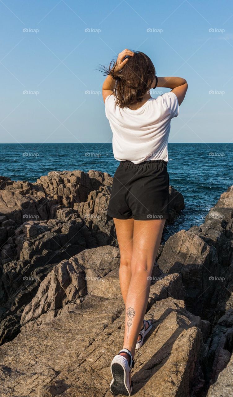 A teenager girl with tattoo on her leg from behind 