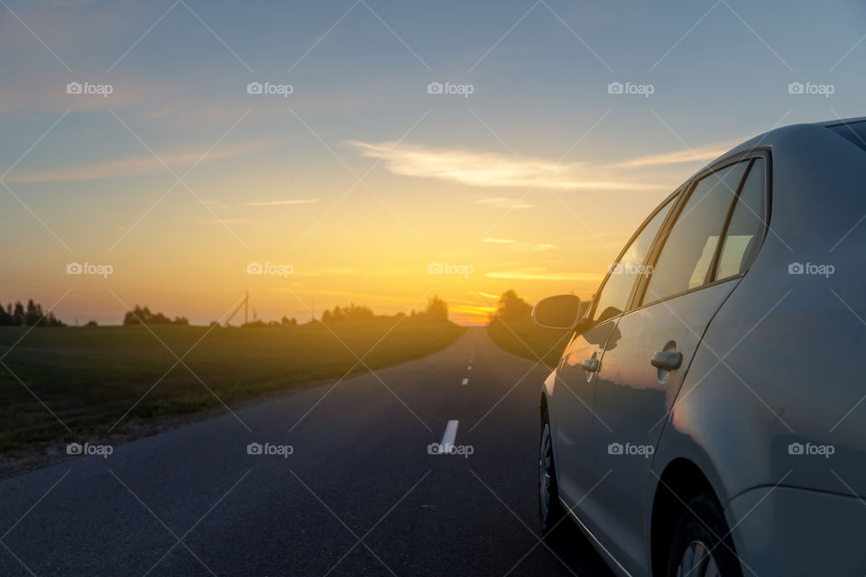 Car driving into the sunset, traveling by car concept