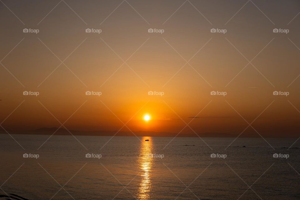 Sunrise in Paralia Greece with a boat in the middle