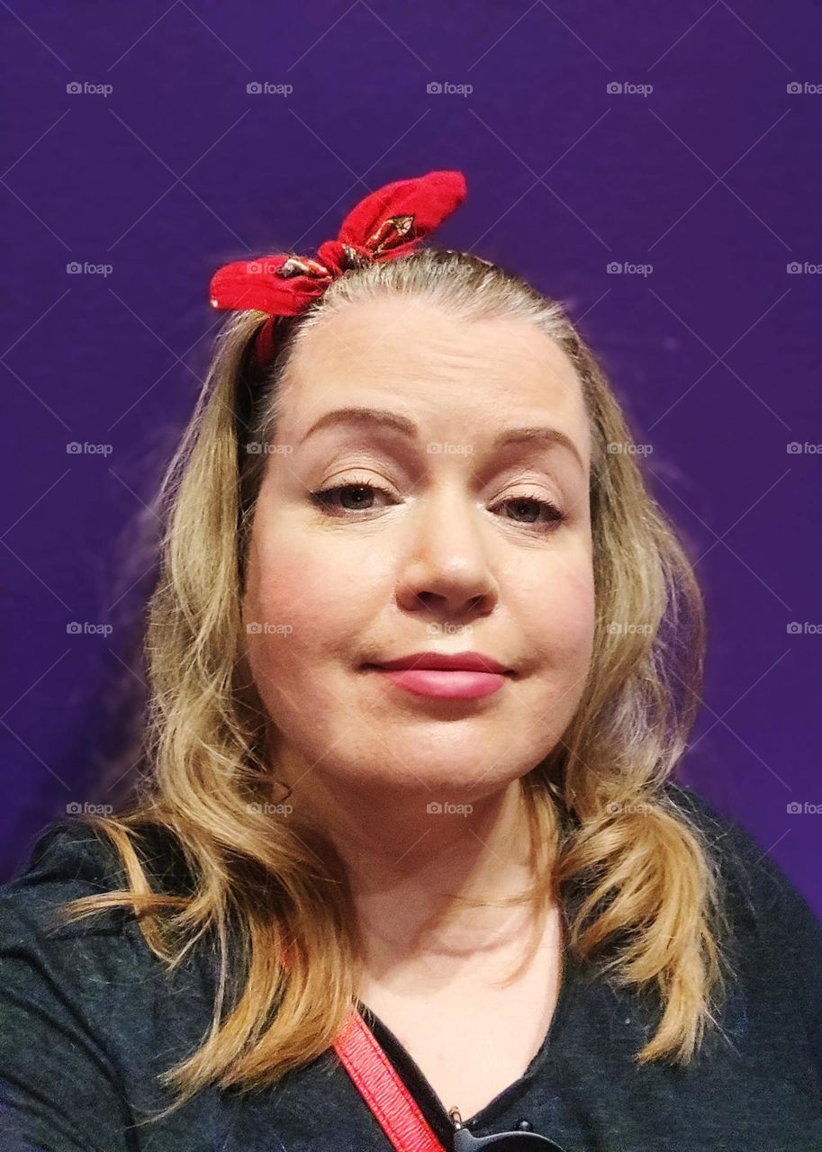 Close up portrait of lightly smiling women with red scarf on her head with the deep purple background