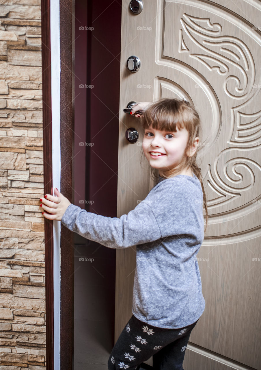 A little beautiful girl opens the door to the Playground of the house.