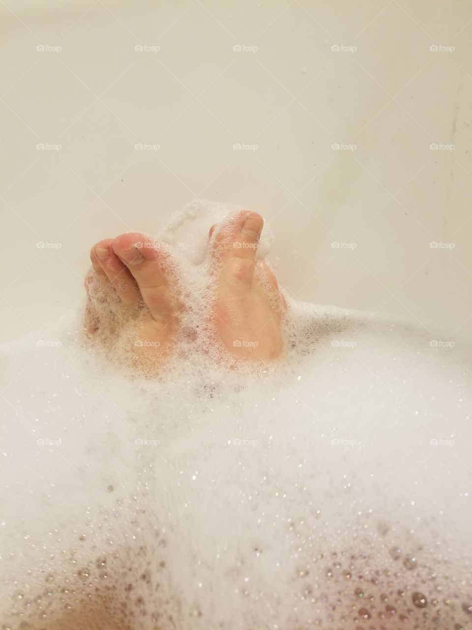 Feet covered in soap foam during bubble bath