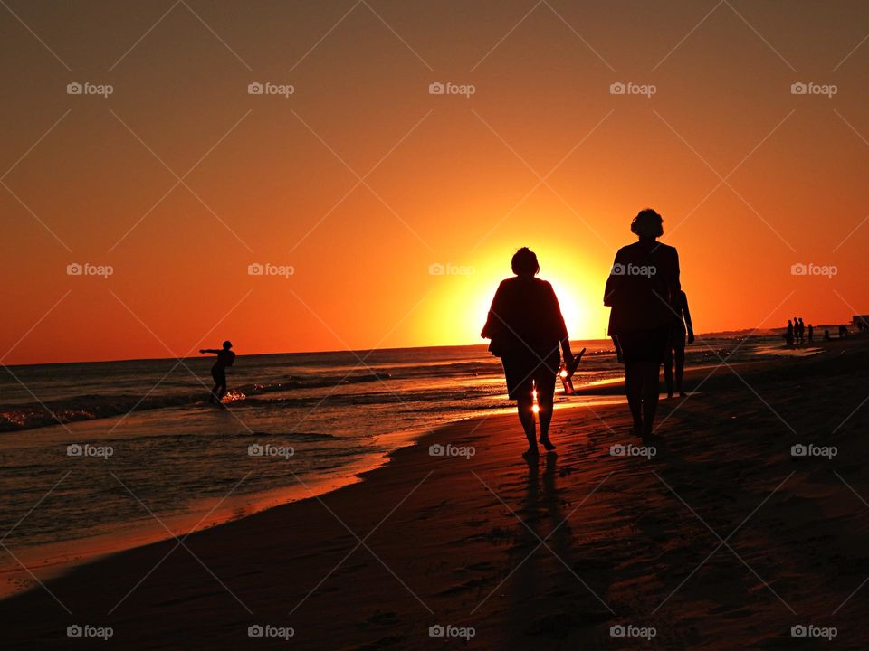 Watching the sunset, gulf of mexico - people in silhouette watching a brilliant sunset over the water of the Gulf of Mexico beach in December