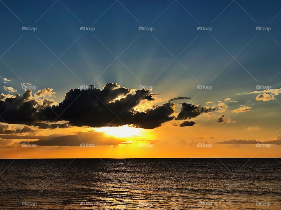 Celestial golden sunset bursting over the ocean.