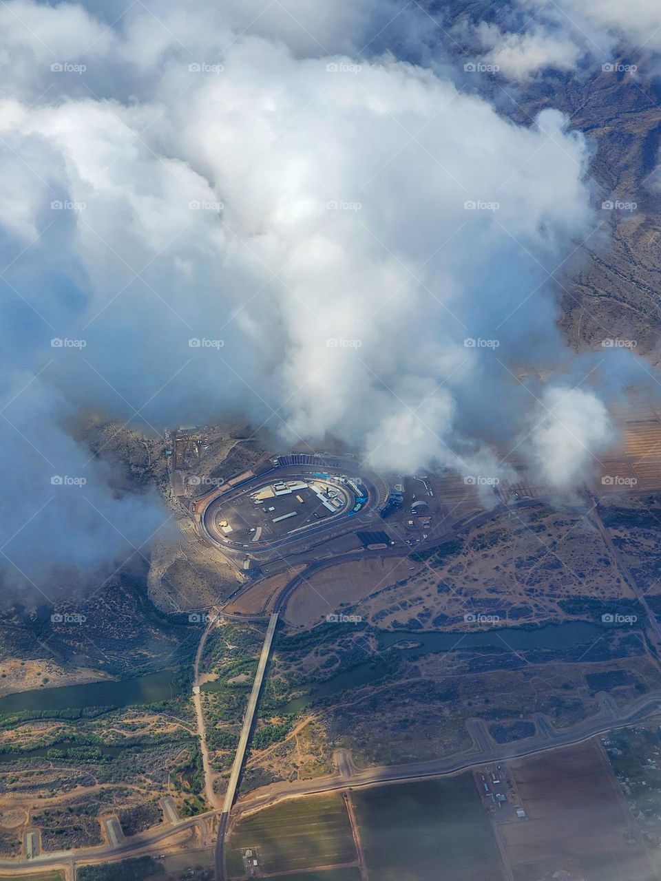 The Phoenix International Raceway racetrack peaks through the clouds shortly after taking off from Phoenix Sky Harbor Airport