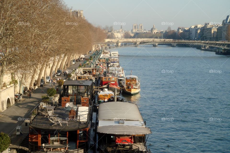 people walking in a promenade next to the Seine River and lots of boats