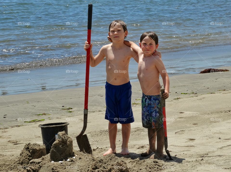 Young Boys On The Beach. Two Young Brothers Digging Sand On The Beach
