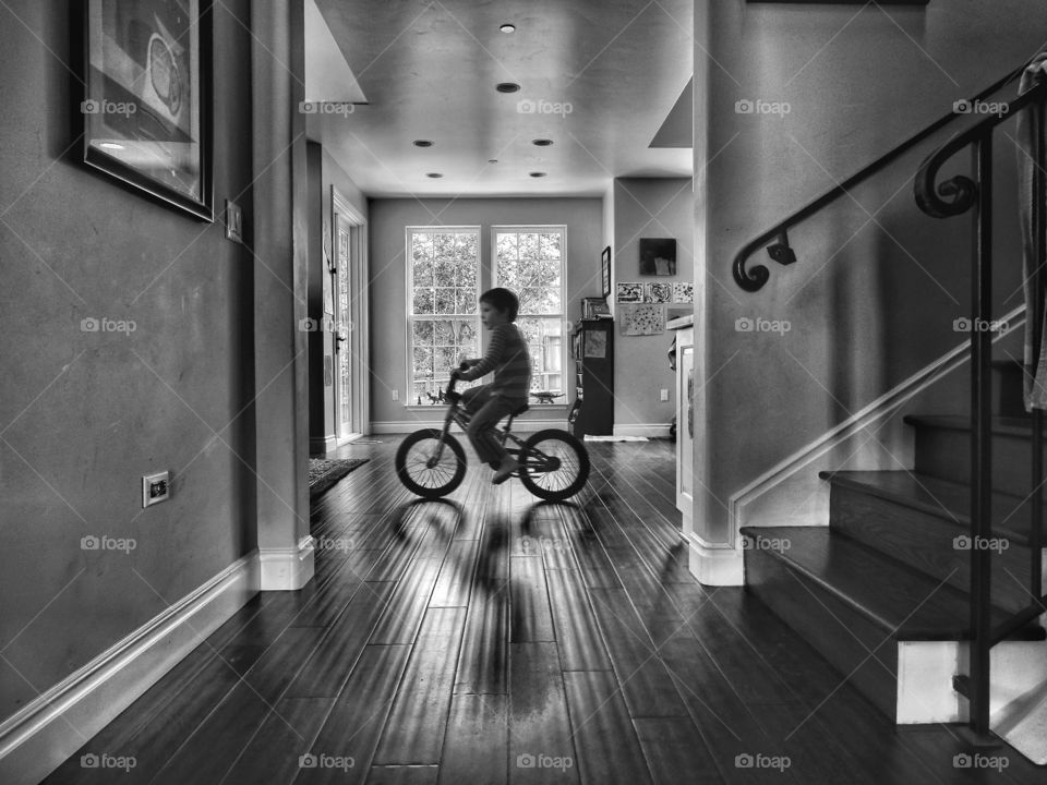 Black And White Architecture. Contemporary Open Plan House With Boy Riding Bicycle Indoors
