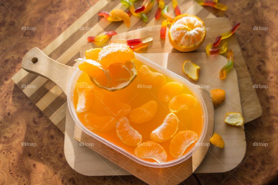 Delicious orange jelly with tangerine slices in a container and jelly worms.