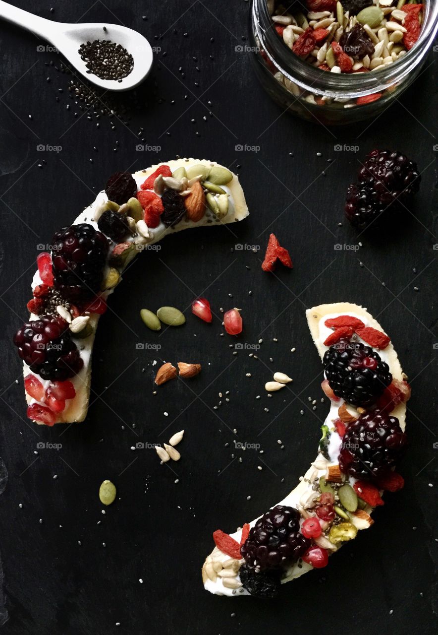 Banana split with topped with greek yogurt blackberries and healthy seeds 