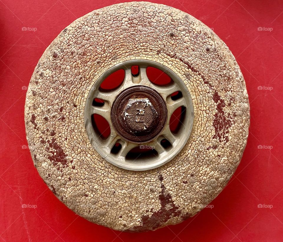 Close up of an old cracked rollerblade wheel on a bright red background