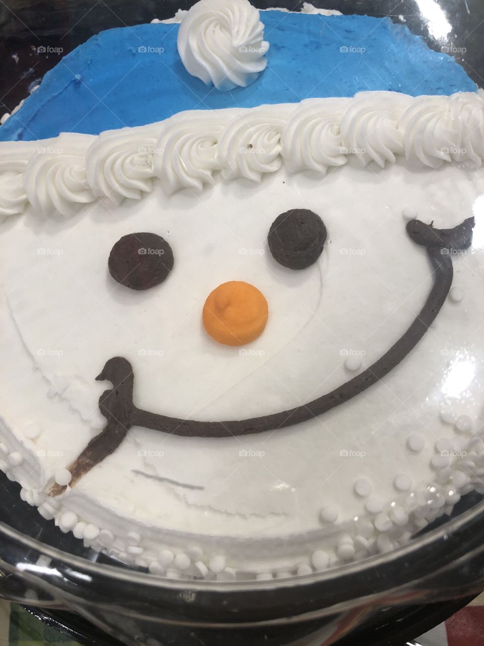 A closeup of a delicious smiling snowman cake. 
