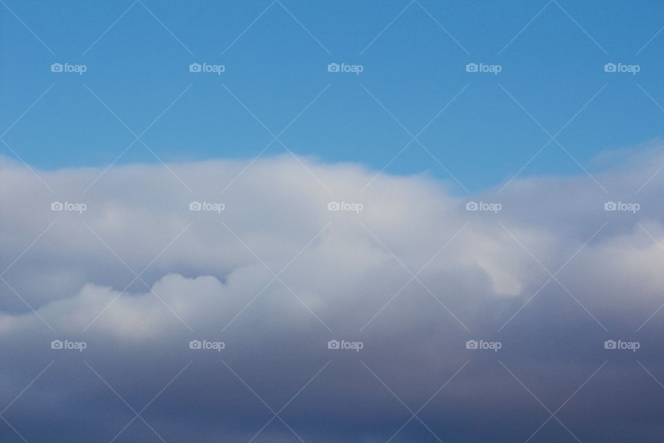 Blue sky above billowy clouds blowing in before a storm