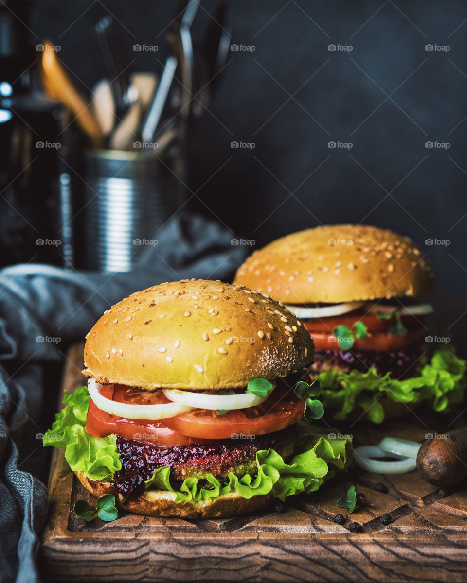 Burgers with veggies on wooden board