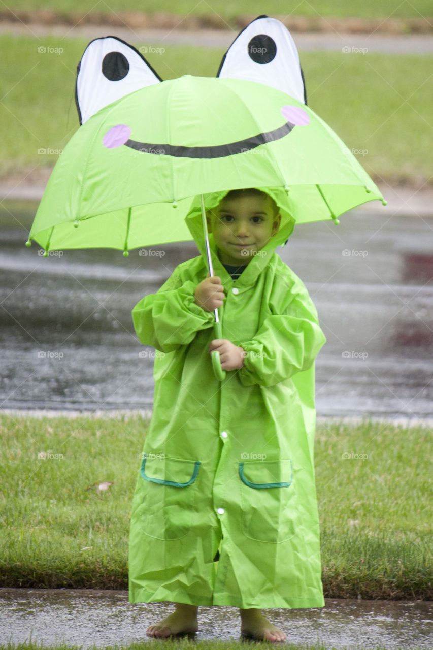 Portrait of a boy with green raincoat and umbrella