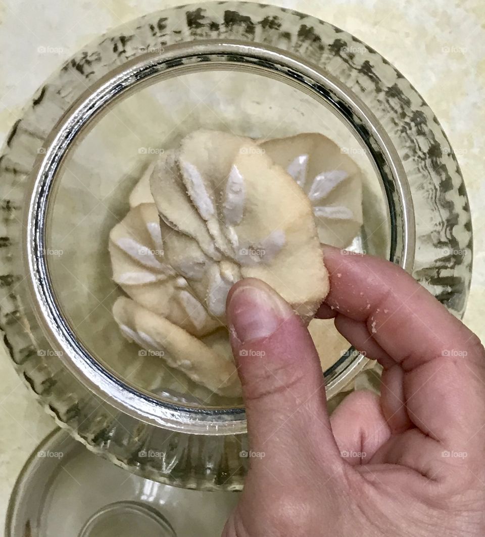Persons hand taking a cookie from the cookie jar