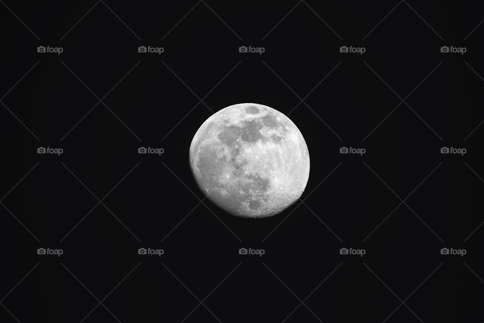 A close shot of the moon in the infinite darkness we call space. it is an almost full moon.