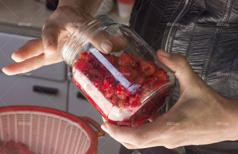 Prepares raspberries with sugar, sweet dessert in jars