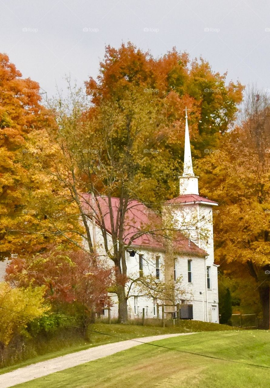 Country church with beautiful trees covered in golden leaves